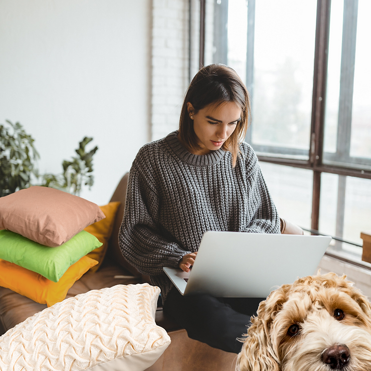girl working at home with a laptop and her dog sitting nearby