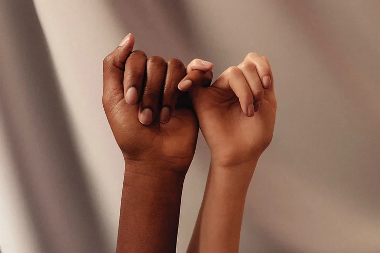 a black and brown hand holding pinky fingers