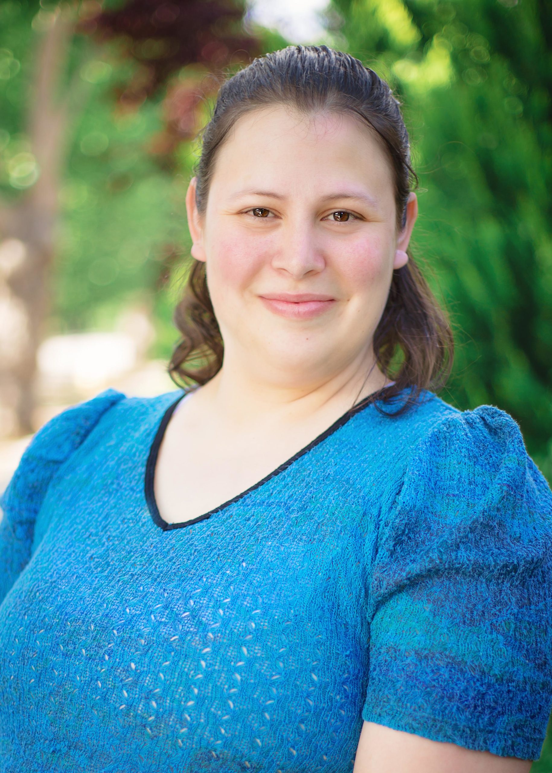 Desi Bolin- Woman with brown hair, dark eyes, and blue top, smiling